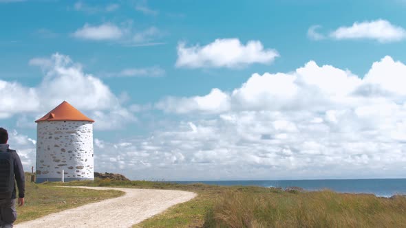 Man walking near a windmill by the ocean