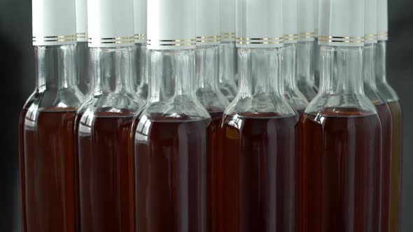 Glass Bottles with Alcoholic Drink Rotate on Conveyor