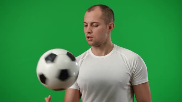 Medium Shot Portrait of Young Caucasian Sportsman Spinning Football Ball on Finger in Slow Motion alt