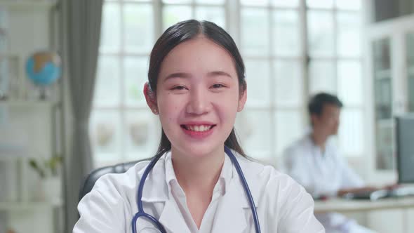 Asian Female Doctor Physician In White Medical Uniform Speaking to Camera During Video Conference alt