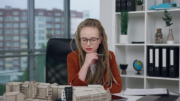 Woman with Dreadlocks Looking at Camera in Modern Design Office Agency alt