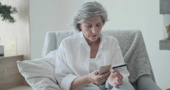 Happy Mature Old Female Customer Holding Banking Credit Card and Buying Goods alt