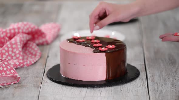 Female Hands Decorate Homemade Strawberry Mousse Cake with Sugar Flowers alt