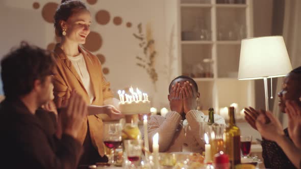 Happy Afro-American Man Blowing Candles on Cake and Birthday Party alt
