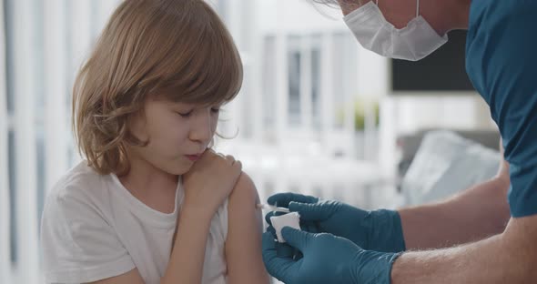 Close Up of Aged Doctor in Protective Mask and Gloves Vaccinating Preteen Boy alt