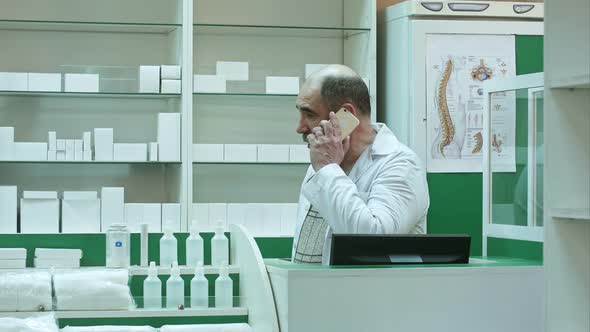 Pharmacist Consulting Customer Via Cell Phone in Drug Store alt