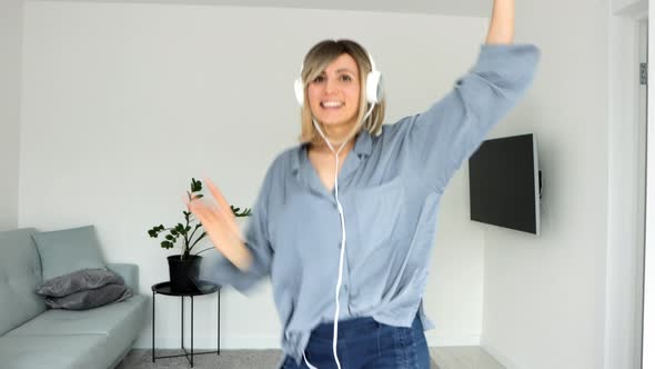 Cheerful woman in headphones listening to music, beautiful girl singing favorite song, dancing