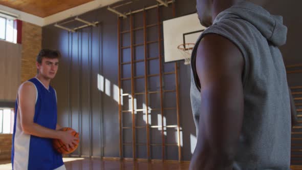 Caucasian male basketball player and coach practicing shooting with ball alt