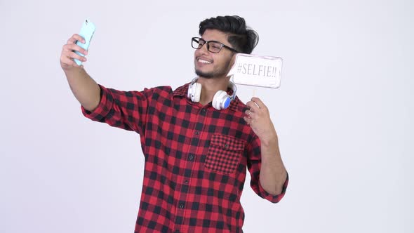 Young Happy Bearded Indian Hipster Man Taking Selfie with Paper Sign alt