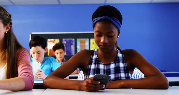 Students using laptop and mobile phone in classroom alt