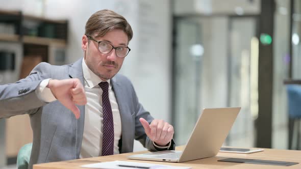 Thumbs Down By Serious Businessman with Laptop in Office  alt