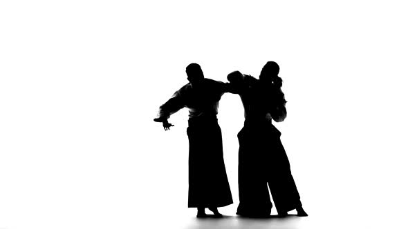 Black Silhuettes of Two Males in Keikogi or Kimono Showing Aikido Using Tanto. Isolated, White. Slow alt
