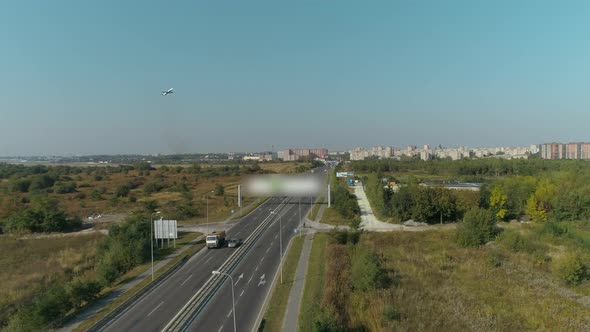 Passenger Plane Takes Off Into the Sky. Aerial View of Highway and Overpass in City. alt