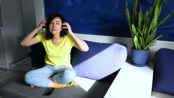 Slow motion woman in casual clothes put on headphones and click on smartphone, listening to podcast alt