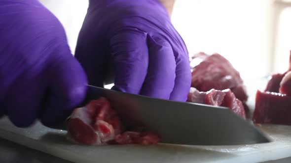Сhef in gloves cuts beef into pieces