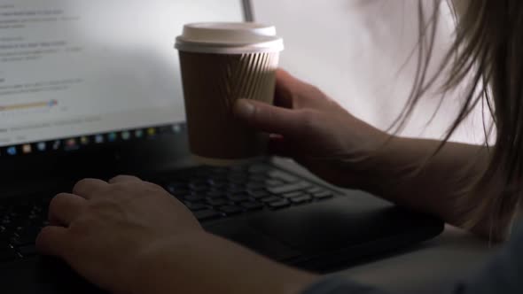 Busy woman working on a laptop in office with takeout coffee close up shot alt