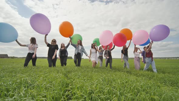 Girls Friends are Walking Across the Field with Large Balloons and Colorful Balloons alt