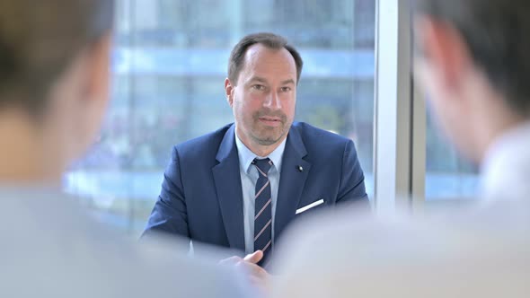 Rear Back View of Couple Having Meeting with Middle Aged Businessman alt