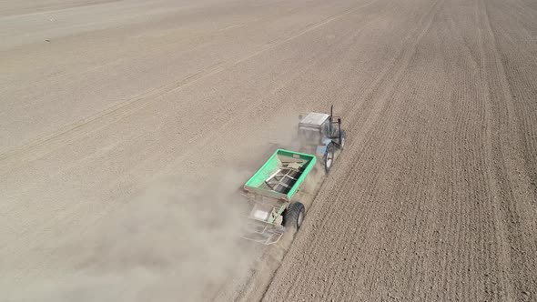 Aerial View  Video of Tractor with Fertilizer Trailer Fertilizes the Field After Planting