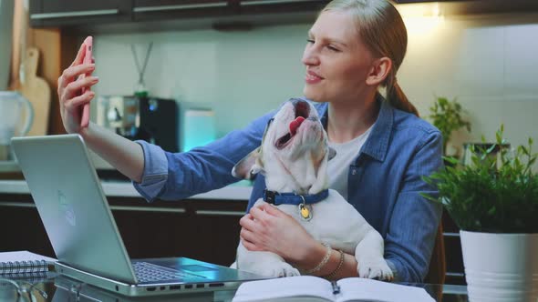 Pretty Woman Making Video Call on Smartphone with a Small Dog on Her Hands