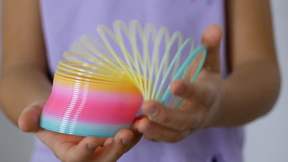 Kid holds a Slinky toy in his hands. A rainbow spiral for games popular in the '90s. alt
