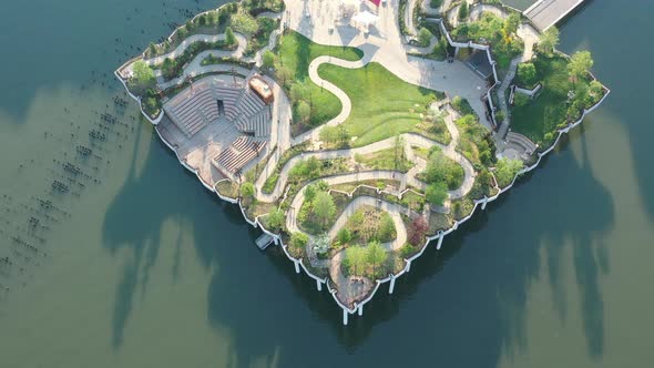 An aerial view of Manhattan's Little Island, a public green space on a sunny day. The drone camera t alt