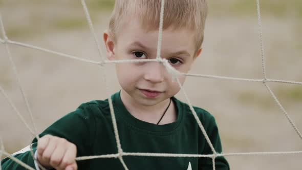 A Sad Boy Looks At The Camera Is Behind A Rope Net, Stock Footage 