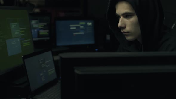 Hacker connecting with his computers in a dark basement