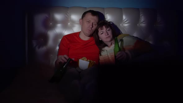 Man and Woman Lie on the Bed Watching Tv Drink Beer and Eating Potato Chips in the Evening Couple