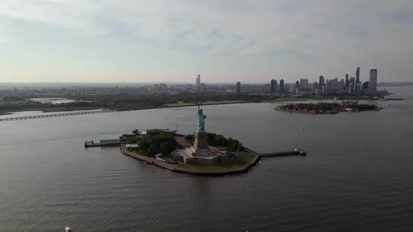 Statue of Liberty in front of New Jersey, sunny, summer day in USA - orbiting aerial alt