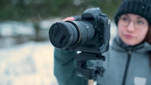 photographer takes off the lens cap of a photo camera outdoors on a snowy day alt