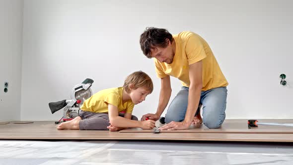 Father and His Little Son Install Laminate on the Floor in Their Apartment alt