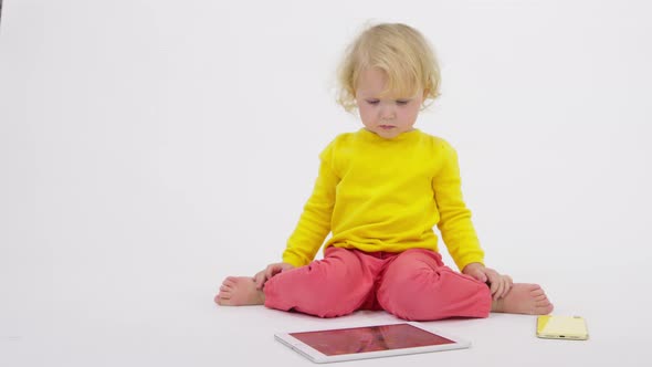 Cute Little Baby Sitting on Floor Skillfully Uses Tablet Phone White Background