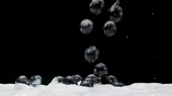 A Blueberries Falling into white yogurt in Slow Motion on a Black Background alt