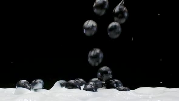 A Blueberries Falling into white yogurt in Slow Motion on a Black Background