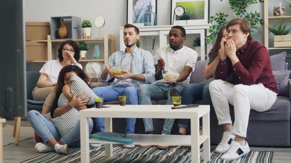 Scared Young People Students Watching Thriller on TV and Eating Snacks at Home alt