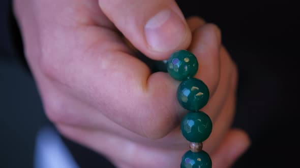 Prayer Beads in Mens Hand on Dark
