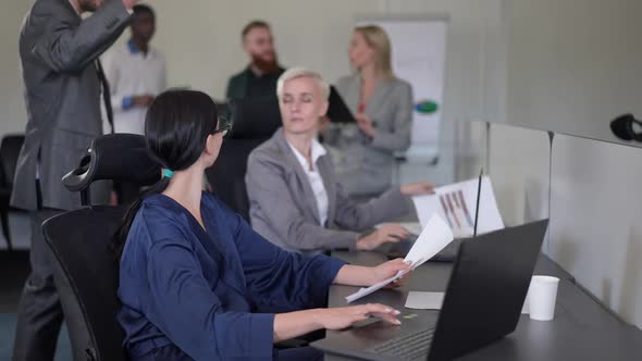 Side View Professional Caucasian Woman Sitting in Office Managing Business As Colleagues Passing alt