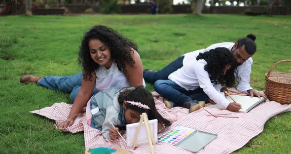 Indian parents having fun at city park painting with their children alt