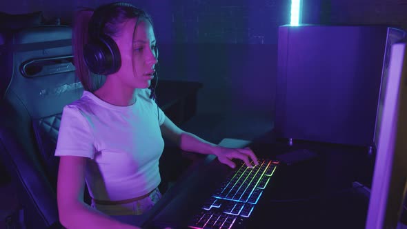 Young Concentrated Gamer Woman Playing Using PC in the Gaming Club alt