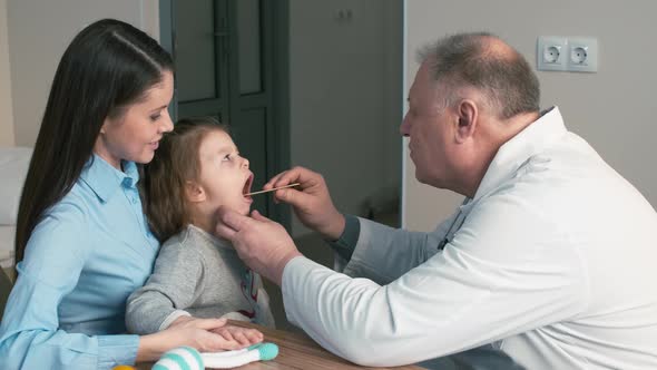 Male doctor examining girl's throat