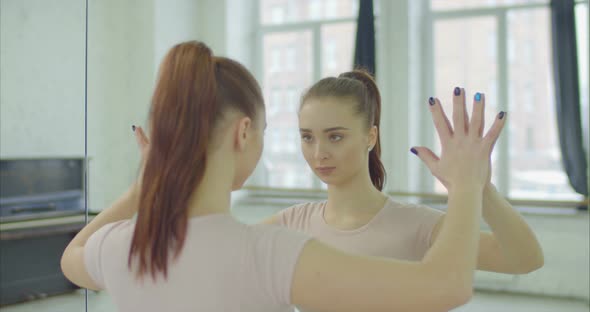 Woman Touching Mirror While Looking at Reflection alt