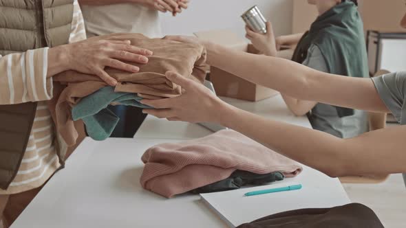 Unrecognizable Woman Taking Clothes from Charity Organization alt