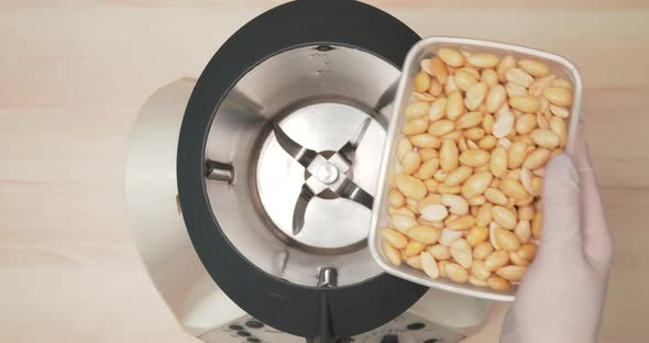 4K - Nuts are filled up into a grinder. Close-up alt