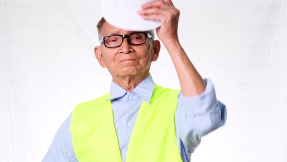 Confident senior engineering architect wearing vest and helmet on white background in studio. alt
