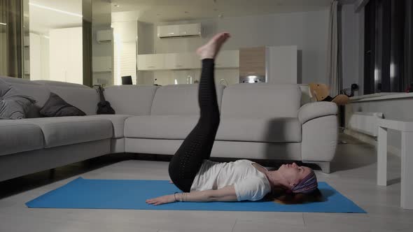 A Girl in Sportswear Performs an Exercise Throwing Her Feet Behind Her Head