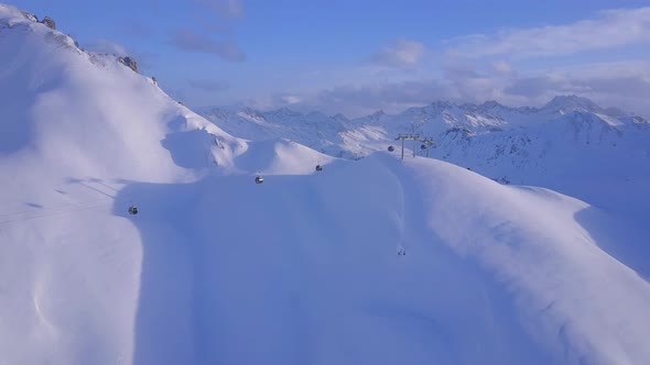 Aerial drone view of a ski gondola lift and mountains at a ski resort alt