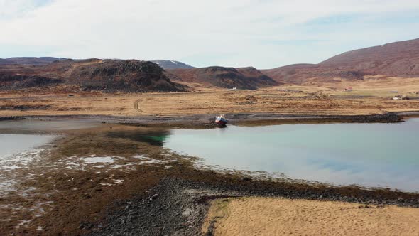 Drone Over Moored Boat In Fjord With Car In Hilly Landscape alt