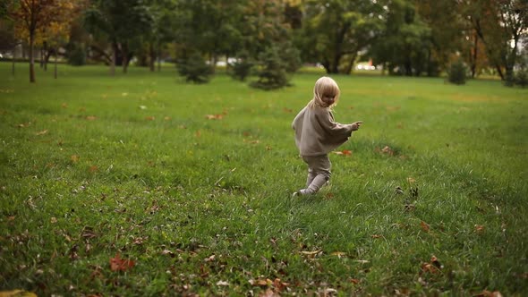 Happy Cute Baby Girl Running Around the Autumn Park