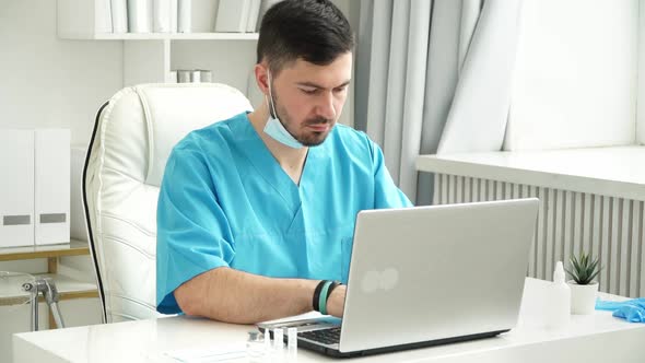 Young Male Doctor Works at Laptop in Clinic
